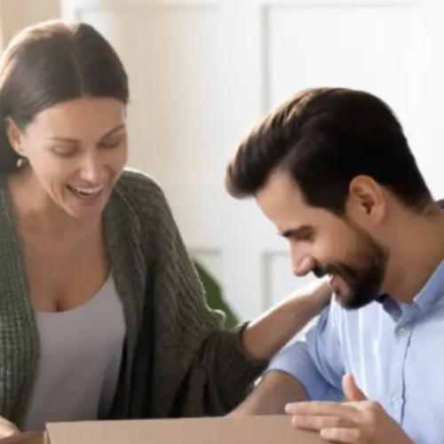 Joyful couple unwrapping gift hamper